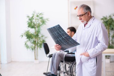Tekerlekli sandalyedeki genç adam ve yaşlı doktor radyoloji uzmanı