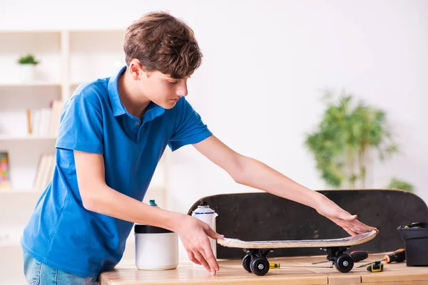 Мальчик чинит скейтборд дома — стоковое фото
