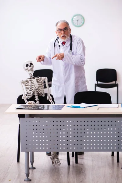 Vecchio medico maschio e paziente scheletro in clinica — Foto Stock