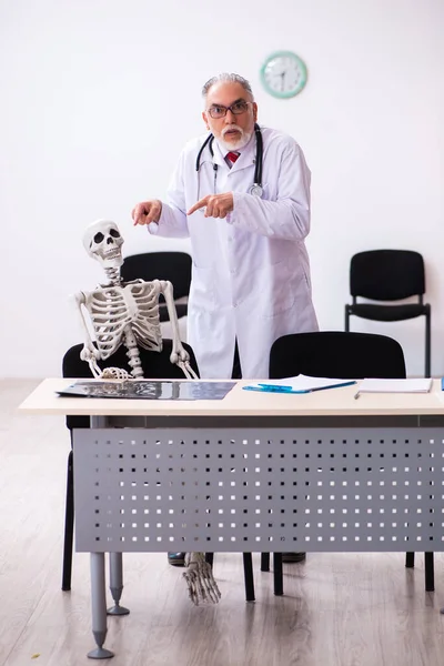 Oude mannelijke dokter en skelet patiënt in de kliniek — Stockfoto