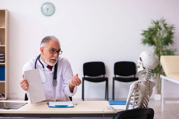 Oude mannelijke dokter en skelet patiënt in de kliniek — Stockfoto