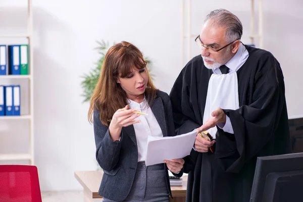 Oude mannelijke rechter en zijn jonge secretaresse op kantoor — Stockfoto