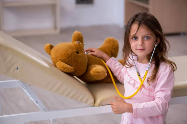 Liten flicka som håller björn leksak väntar på läkare på kliniken — Stockfoto