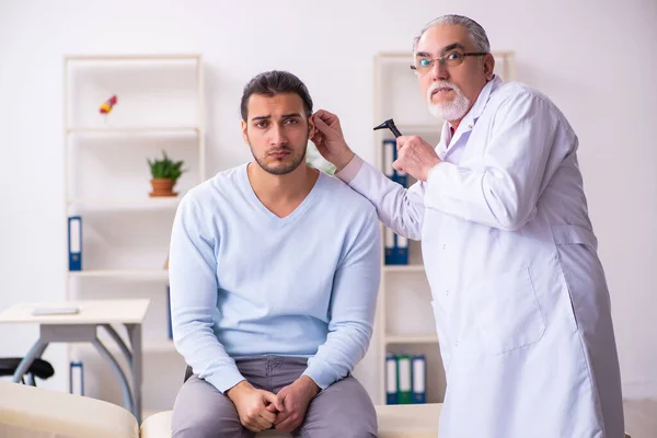 Genç hasta bir adam yaşlı bir doktoru ziyaret ediyor. — Stok fotoğraf