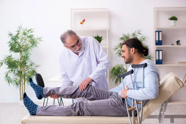 Genç bacağı yaralı adam yaşlı doktor osteopath 'ı ziyaret ediyor. — Stok fotoğraf