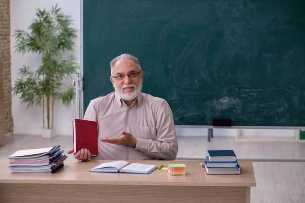 Oude mannelijke leraar zit in de klas — Stockfoto