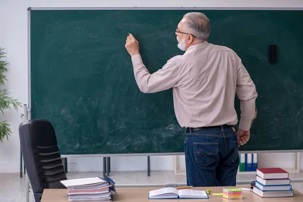 Oude mannelijke leraar zit in de klas — Stockfoto