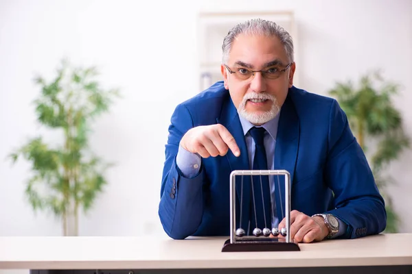 Oude mannelijke werknemer zakenman en meditatie ballen op het bureau — Stockfoto