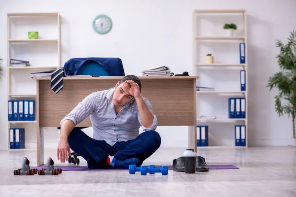 Jovem bonito masculino empregado fazendo exercícios no escritório — Fotografia de Stock