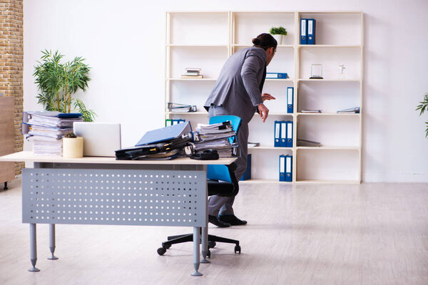 Молодой работник мужчина недоволен чрезмерной работой