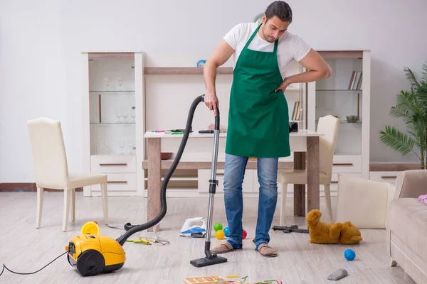 Joven contratista masculino limpiando el piso después de la fiesta de los niños — Foto de Stock