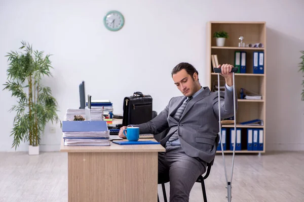 Junge am Bein verletzte männliche Angestellte bei Büroarbeit — Stockfoto