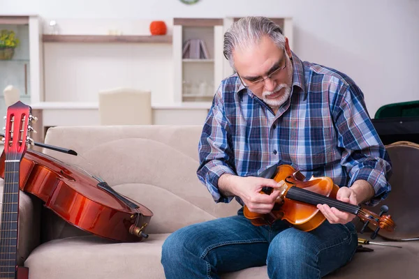 Seniorchef repariert Musikinstrumente zu Hause — Stockfoto