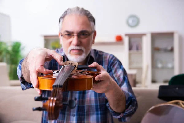 Reparador sênior do sexo masculino reparando instrumentos musicais em casa — Fotografia de Stock