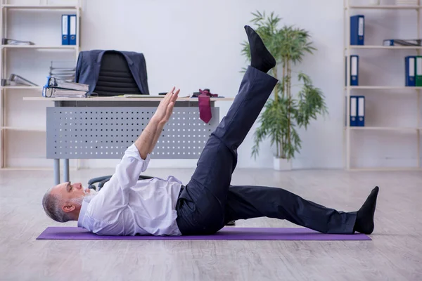 Empleado varón envejecido haciendo ejercicios físicos durante el descanso — Foto de Stock