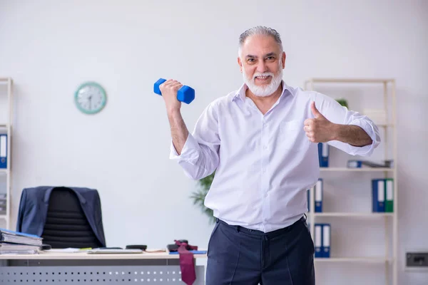 Verouderde mannelijke werknemer doet fysieke oefeningen tijdens de pauze — Stockfoto