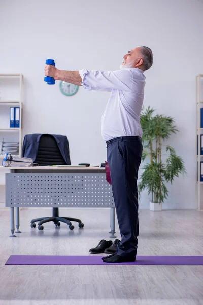 Ältere männliche Mitarbeiter machen in der Pause körperliche Übungen — Stockfoto