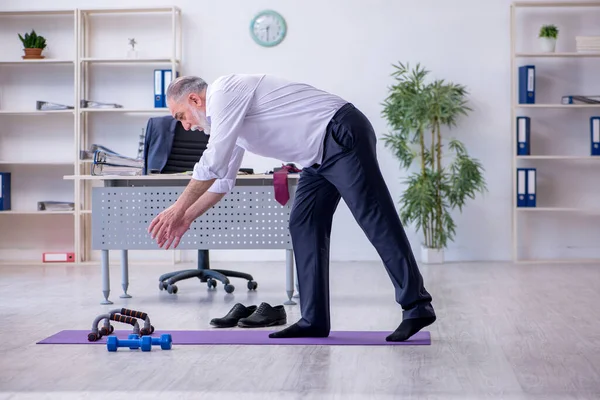 Åldrad manlig anställd som motionerar under pausen — Stockfoto