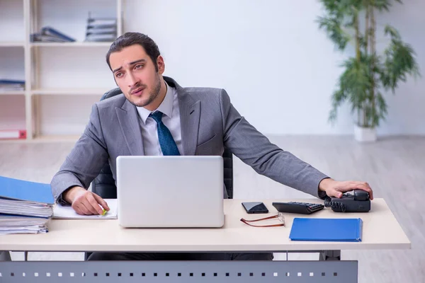 Joven empleado masculino descontento con el trabajo excesivo en la oficina — Foto de Stock