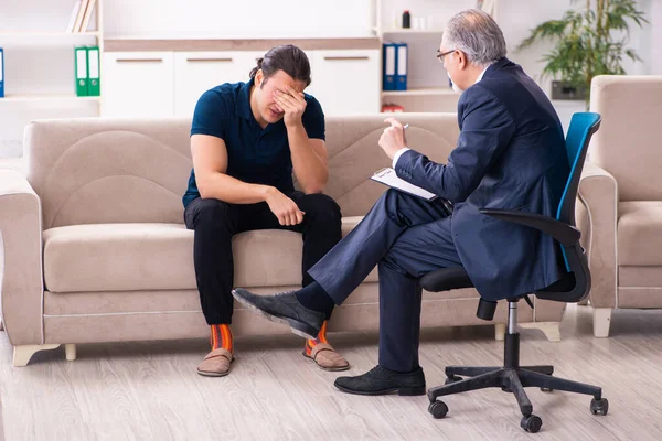 Young man visiting old male psychologist — Stock Photo, Image