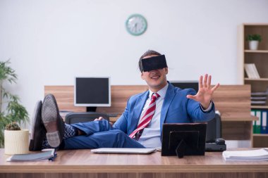 Ofiste sanal gözlük takan genç bir erkek çalışan.