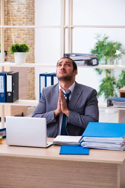 Ung manlig anställd och för mycket arbete på kontoret — Stockfoto