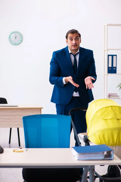 Joven empleado masculino que cuida niños en el lugar de trabajo —  Fotos de Stock