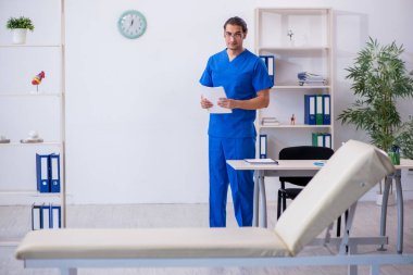 Genç erkek doktor hastanede not alıyor.