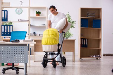 İş yerinde yeni doğan bebeğe bakan genç bir erkek işçi.