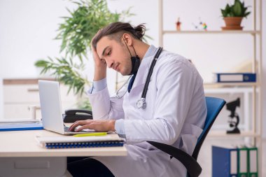 Klinikte çalışan genç erkek doktor.