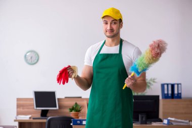 Genç müteahhit ofisi temizliyor.