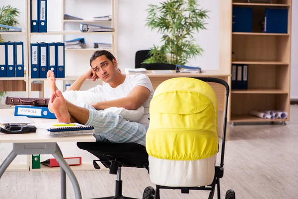 Joven empleado masculino que cuida del recién nacido en el lugar de trabajo — Foto de Stock