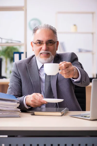 Un vieil employé boit du café au bureau — Photo