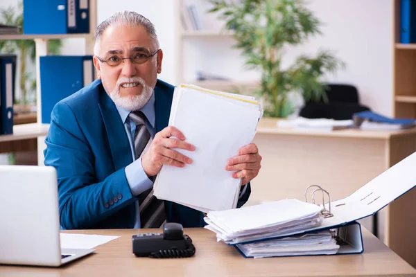 Oude mannelijke boekhouder ongelukkig met buitensporig werk op de werkplek — Stockfoto