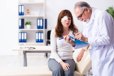 Genç kadın yaşlı erkek doktor göz doktorunu ziyaret ediyor.