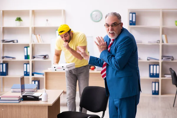 Junger männlicher Kurier liefert Pizza ins Büro — Stockfoto