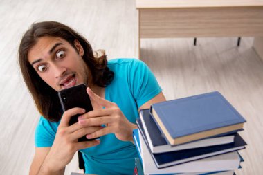 Genç bir erkek öğrenci ve sınıfta bir sürü kitap var.