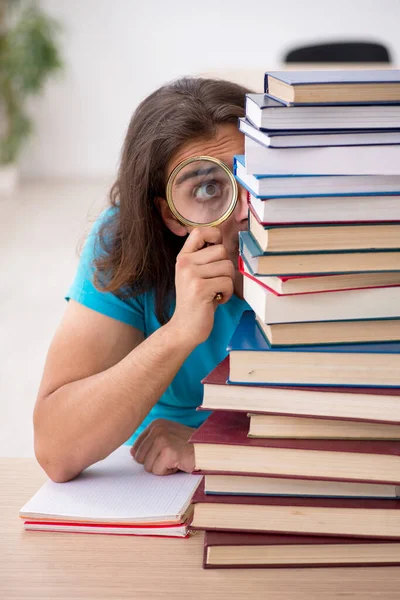 Jonge mannelijke student en veel boeken in de klas — Stockfoto