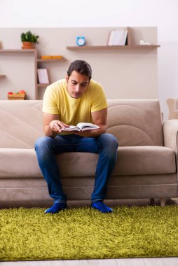 Evde kitap okuyan genç bir erkek öğrenci.