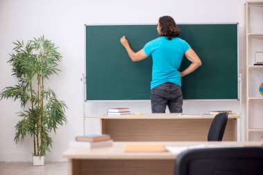 Yeşil panonun önünde genç bir erkek öğrenci.