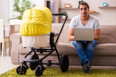 Genç erkek müteahhit evde yeni doğan çocuğa bakıyor.