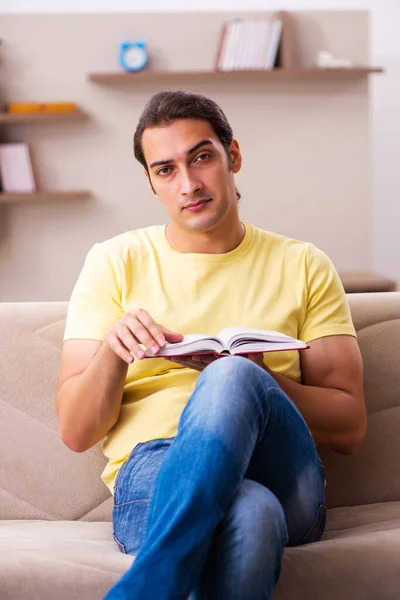 Giovane studente di sesso maschile libro di lettura a casa — Foto Stock