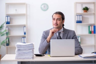 Ofisteki aşırı işten memnun olmayan genç bir erkek işçi.