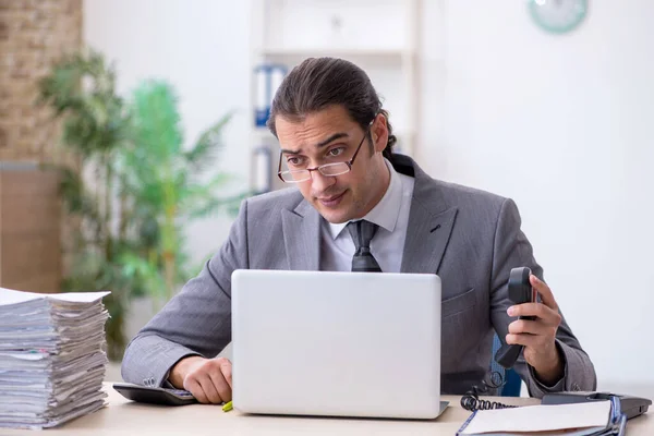 Ung manlig anställd pratar per telefon på kontoret — Stockfoto