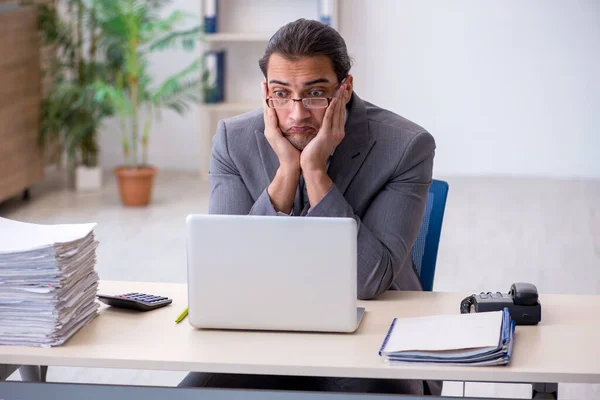 Giovane dipendente maschio infelice con un lavoro eccessivo in ufficio — Foto Stock