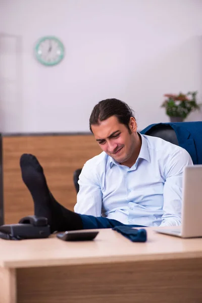 Joven empleado masculino haciendo ejercicios físicos en el lugar de trabajo — Foto de Stock