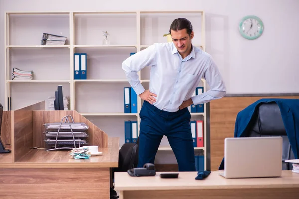 Jovem funcionário do sexo masculino fazendo exercícios físicos no local de trabalho — Fotografia de Stock