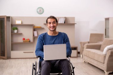 Evde acı çeken tekerlekli sandalyedeki genç adam.