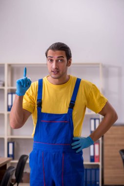 Genç müteahhit ofisi temizliyor.