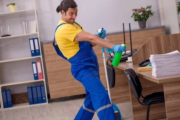 Junge männliche Auftragnehmer putzen das Büro — Stockfoto